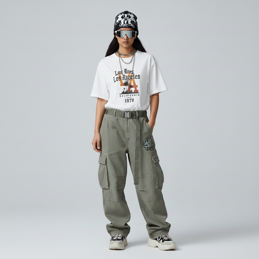 Person wearing a white t-shirt with text and graphics, green cargo pants, and a black and white cap on a gray background