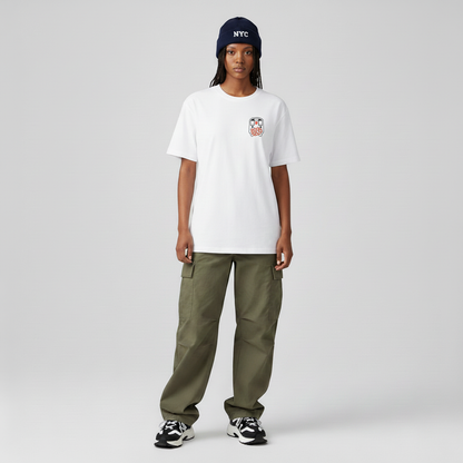 Person wearing a white t-shirt with a logo, green pants, and a navy beanie with 'NYC' on a gray background